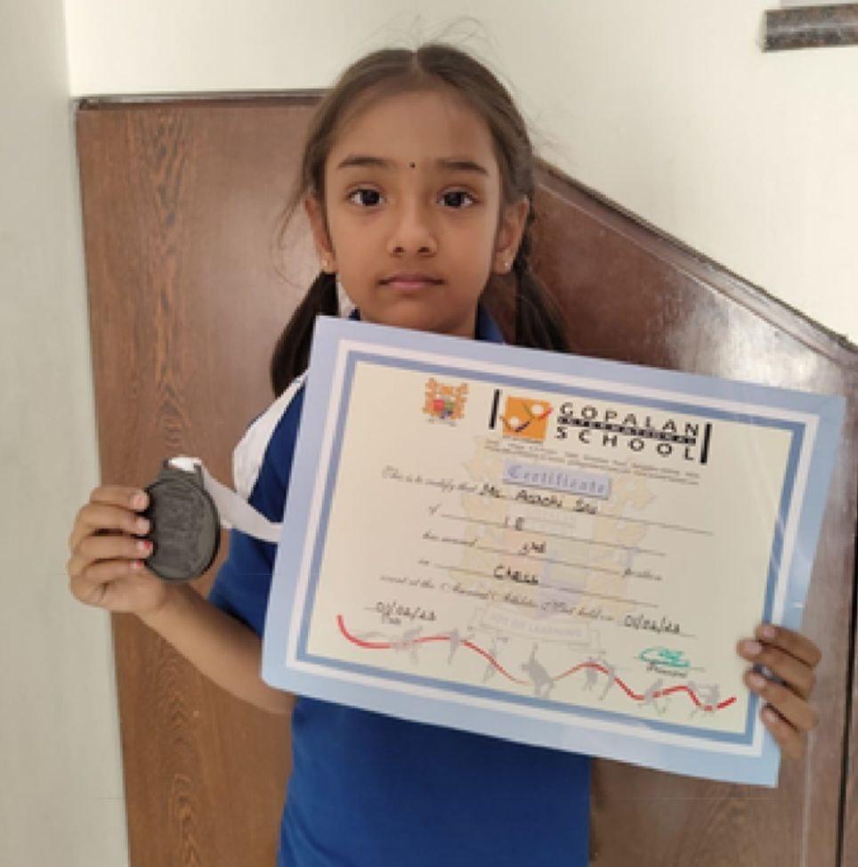 OMCA student with a chess achievement certificate and medal